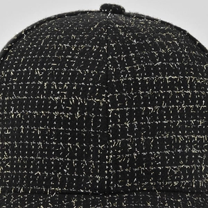 Gros plan sur la texture en tweed noir et doré de la couronne d'une casquette