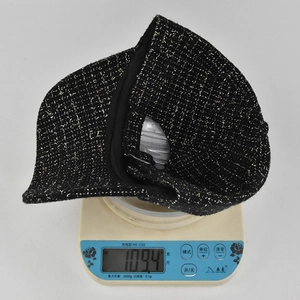 Vue détaillée d'une casquette en tweed noir avec fil doré pesant 109,4g sur balance