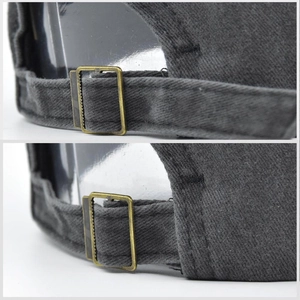 Close-up of the vintage bronze metal buckle and dark gray cotton fabric on a USA baseball cap