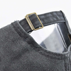 Close-up of washed cotton baseball cap with adjustable bronze buckle and strap detail