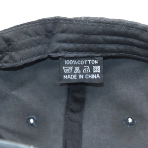 Close-up of 100% cotton washing label and stitching details on black baseball cap