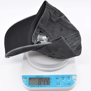 Close-up of a washed cotton baseball cap on a scale showing its lightweight of 84.4g