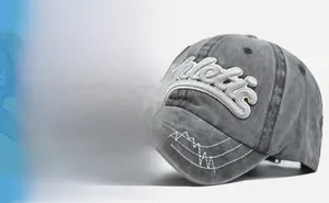 Detail of grey washed denim baseball cap with 3D embroidery and wavy brim stitching