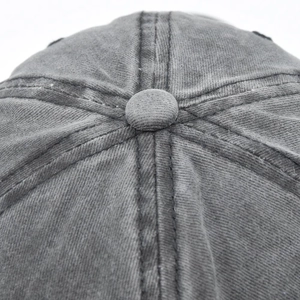 Close-up of top button and reinforced stitching on washed grey cotton baseball cap