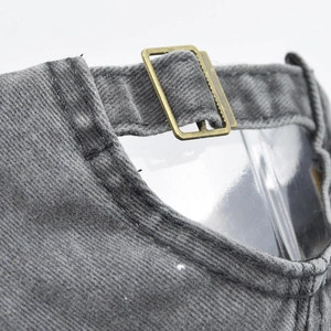 Detail of adjustable brass buckle and vintage washed grey denim strap on baseball cap