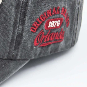 Detailed macro view of red and white 3D embroidery on a washed grey baseball cap