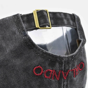 Detail of washed denim baseball cap with adjustable metal buckle and Orlando embroidery