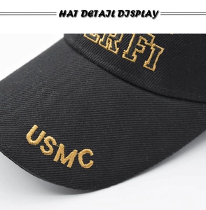 Detailed view of USMC golden embroidery on the brim of a black cotton tactical baseball cap