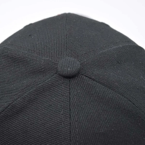 Detailed macro view of the black cotton baseball cap crown with stitched button and seams