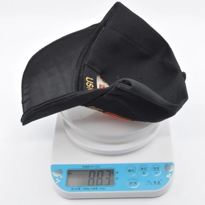 Lightweight black tactical USA baseball cap weighing approximately 88.3 grams on a digital scale