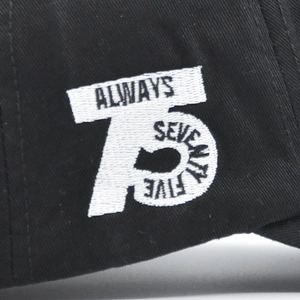 Close-up of white 75 ALWAYS SEVENTY FIVE embroidery on black twill cotton baseball cap