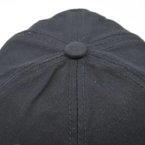 Macro shot of black cotton baseball cap top button and detailed stitching texture