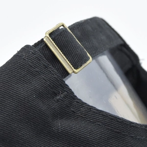 Adjustable black cotton baseball cap with vintage bronze buckle closure detail view
