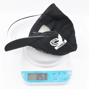 Weight measurement detail of the black and white baseball cap showing 85.1g on a scale