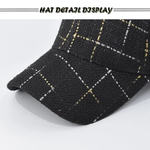 Close-up of black plaid baseball cap with woven gold and silver metallic thread detail