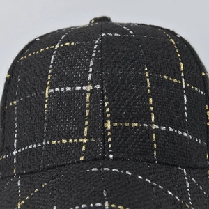 Close-up of black plaid baseball cap featuring gold and silver tweed fabric texture