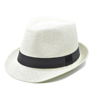 Detailed close-up of woven paper straw texture and black ribbon on a white jazz fedora hat
