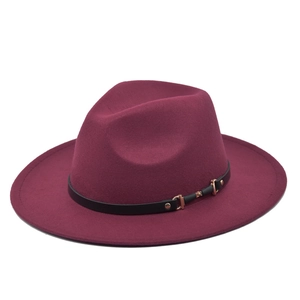 Close-up of wine red fedora hat with wide brim, black leather band, and gold buckle detail