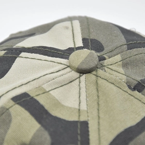 Detail view of the camouflage baseball cap top showing the button and radial stitching