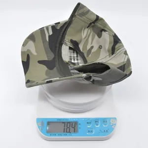 Tactical camouflage baseball cap weighing approximately 78.4g on a digital scale