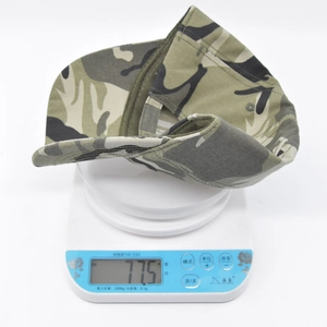 Macro detail showing the weight of the camouflage canvas baseball cap on a digital scale