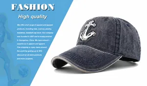 Detailed view of nautical anchor emblem on navy blue washed denim baseball cap