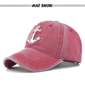 Close-up of red washed cotton baseball cap featuring white rope anchor embroidery detail