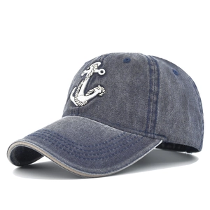Close-up of white anchor embroidery on vintage washed navy blue denim baseball cap
