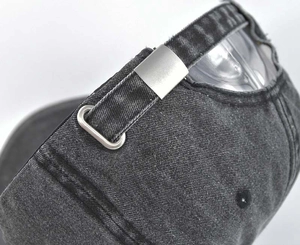 Detail of adjustable metal buckle and vintage washed denim texture on baseball cap