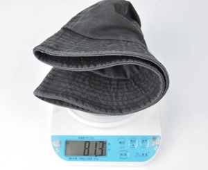 Detail shot showing the lightweight 81.3g washed cotton bucket hat on a digital scale