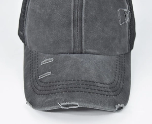 Detailed macro view of distressed holes and washed canvas fabric on the ponytail cap