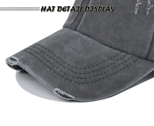 Detail view of washed dark grey baseball cap featuring distressed rips and vintage cotton texture