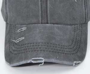 Close-up of distressed washed grey cotton baseball cap with ripped details and stitching