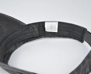 Detail view of the wash label on a 100% cotton black distressed sun visor cap