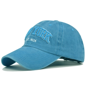 Macro view of white 3D New York embroidery and fine stitching on a sky blue cotton baseball cap