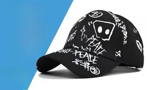 Detailed view of black cotton baseball cap featuring white graffiti peace signs and text