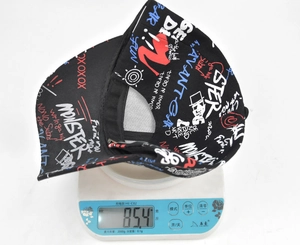 Détail d'une casquette graffiti noire sur une balance électronique affichant 85,4g