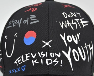 Détail d'une casquette de baseball en coton noir avec graffitis colorés et motifs punk