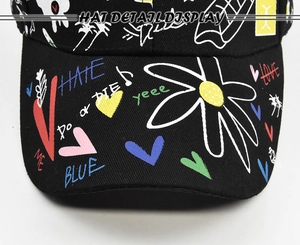 Detailed top view of a black baseball cap featuring vibrant multi-color graffiti prints