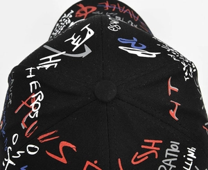 Macro view of black baseball cap crown with colorful graffiti print and top button detail