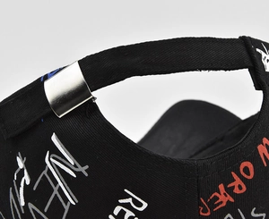 Detailed view of the metal buckle and graffiti print on the back of the black baseball cap