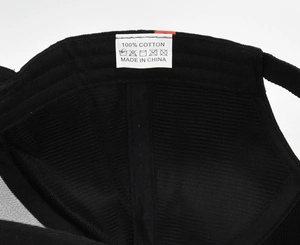 Detail view of the 100% cotton inner lining and wash label of a black baseball cap