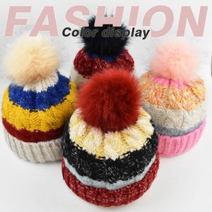 Détail de bonnets en tricot avec pompons en fausse fourrure et motifs colorés