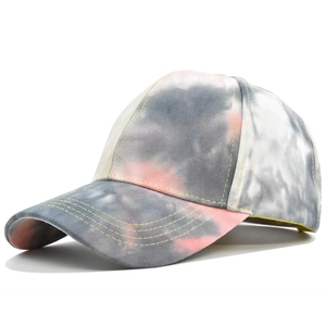 Detail view of tie-dye baseball cap featuring yellow contrast stitching and gray pink colors