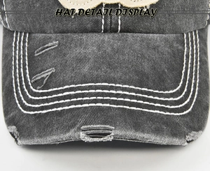 Detail of baseball cap brim with white contrast stitching and distressed ripped edges