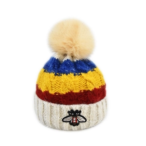 Détail du tricot torsadé épais et broderie d'abeille sur un bonnet d'hiver coloré