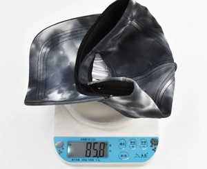 Weight measurement of the black and gray tie-dye baseball cap showing 85.8g on a digital scale