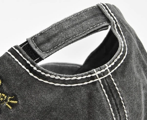 Detail of washed grey baseball cap with velcro back strap and yellow embroidery stitching
