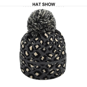 Detailed view of winter beanie featuring leopard print knit and a large pom-pom topper