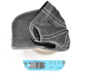 Detailed view showing the 83.6g lightweight vintage washed embroidery baseball cap on a scale